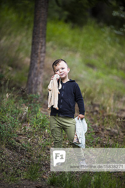 Portrait of toddler boy holding bunny and his small blanket.