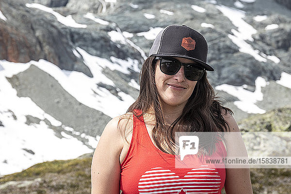 A women hiking in the mountain takes a break and smiles for the camera on a summer day in the mountains of British Columbia.