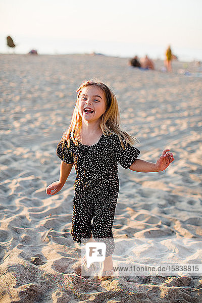 Young Girl Laughing and Playing on Beach at Sunset