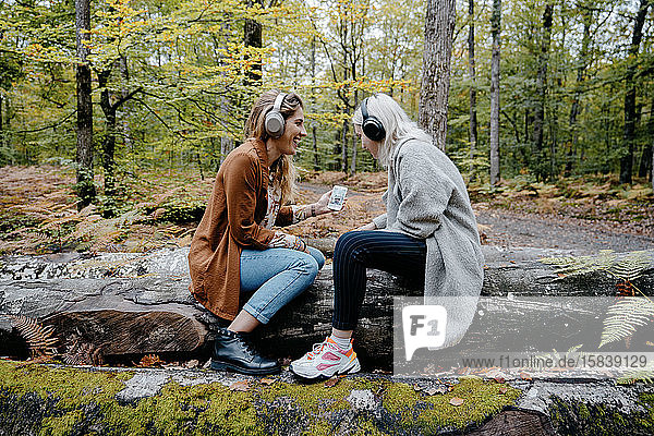 Zwei Frauen streamen ein Video auf ein Smartphone in einem abgelegenen Wald