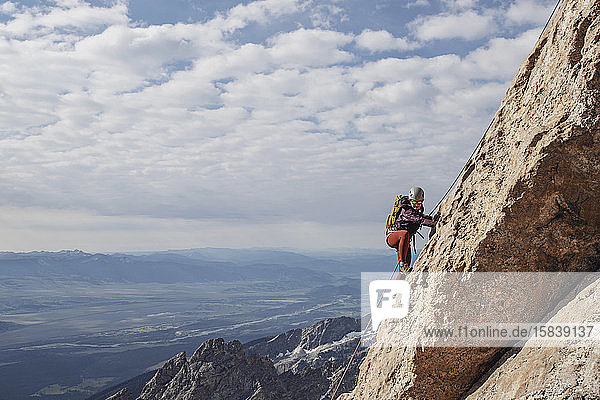 Geschnürte Bergsteigerin besteigt eine Klippe in den Tetons  Wyoming