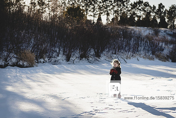 Kleines Mädchen spielt auf gefrorenem  schneebedecktem See