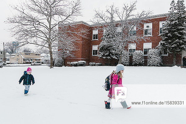 Two children walk to school in the snow.