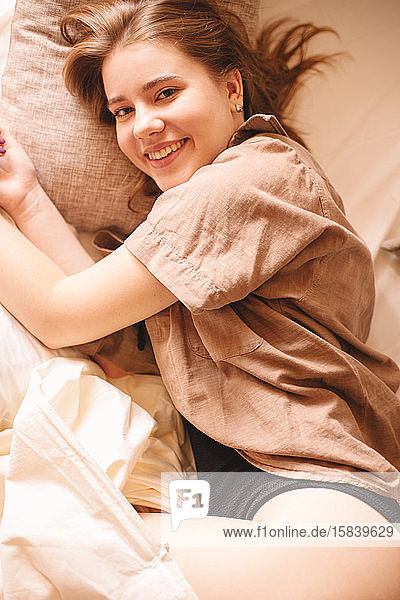 Young cheerful woman lying in bed at home