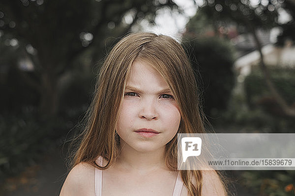 Portrait of a young girl with a serious face standing outside