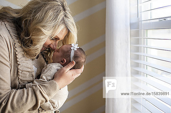 Mother happily holding newborn daughter up to face at home