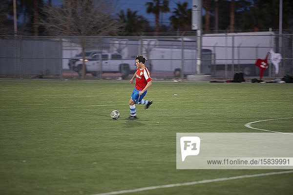 Teen soccer player dribbling the ball during a game