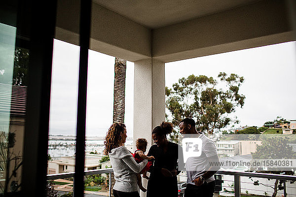 Gemischte Familie steht auf Balkon mit Blick auf den Ozean