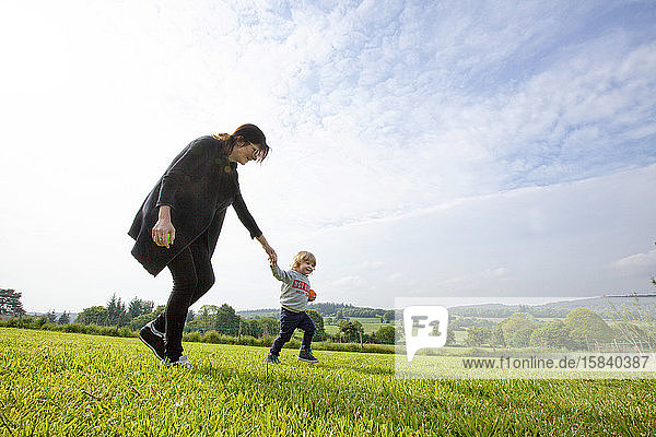 ein kleiner Junge und seine Mutter amüsieren sich auf einer grünen Wiese auf dem Land  Caurel Bretagne  Frankreich.