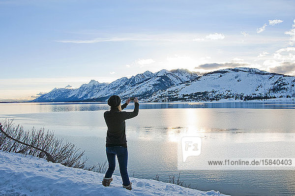 Frau macht ein Foto mit einem Smartphone von Jackson Lake und Teton Range