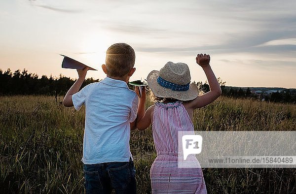 Bruder und Schwester schauen in die Ferne und spielen bei Sonnenuntergang