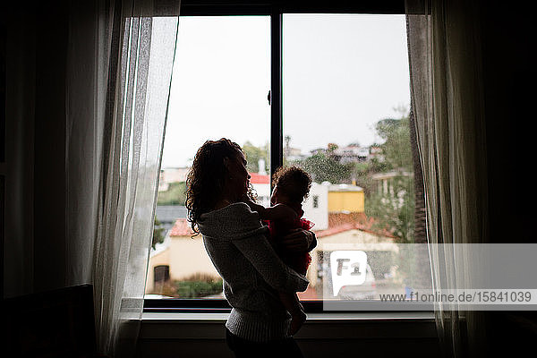 Ende Dreissiger Jahre Mutter hält Baby vor dem Fenster für Silouette