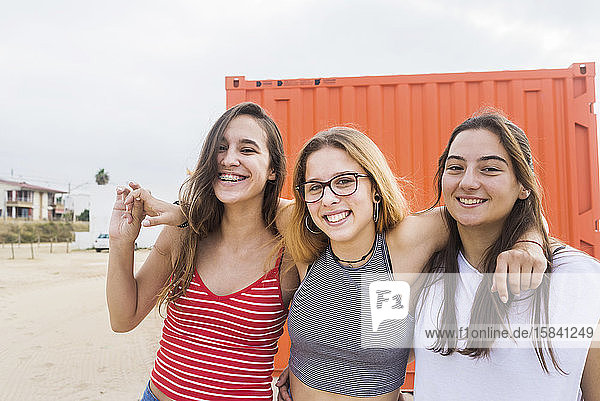 Drei junge glückliche Teenager-Mädchen haben Spaß an oranger Wand