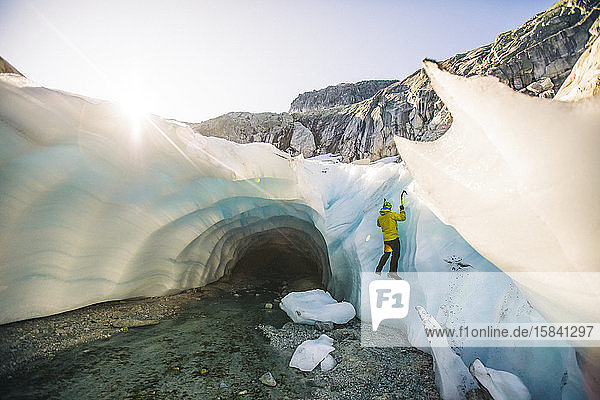 Rückansicht des Eismannes  der außerhalb der Gletscherhöhle klettert.
