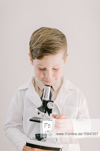 Young child in labcoat looking into a microscope