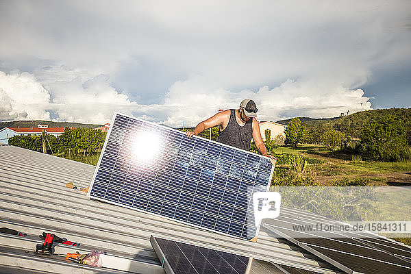 Arbeiter installiert Sonnenkollektoren auf dem Dach des Gebäudes.