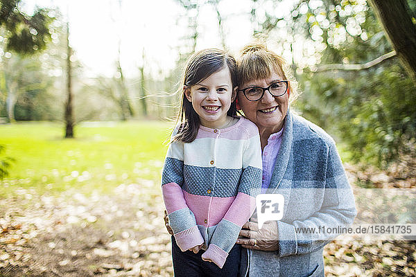 Grandma holds granddaughter in outdoor setting.