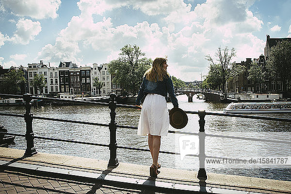 Frau in weißem Kleid mit Blick auf Stadt und Kanal