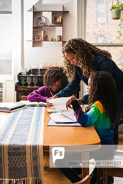 Mature woman assisting daughters in studies at home