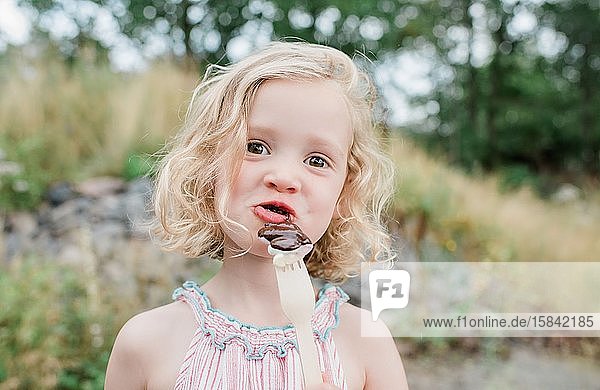 lustiges Porträt eines jungen Mädchens  das Schokolade und Marshmallows isst