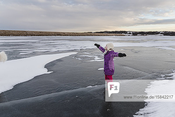 Kleines Mädchen spielt auf gefrorenem See