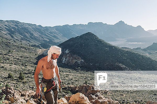 Upper body of shirtless male climber standing in mountain