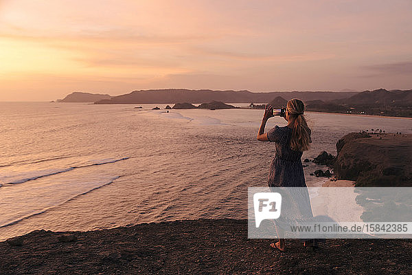 Junge Frau an der Küste bei Sonnenuntergang