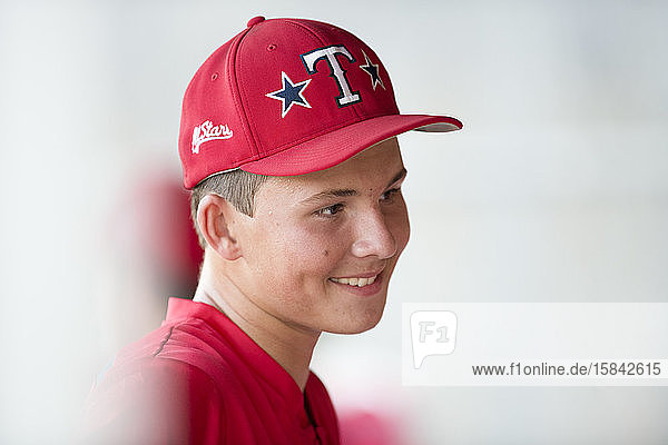 Nahaufnahmeportrait eines jugendlichen Baseball-Spielers in roter Mütze und Uniform