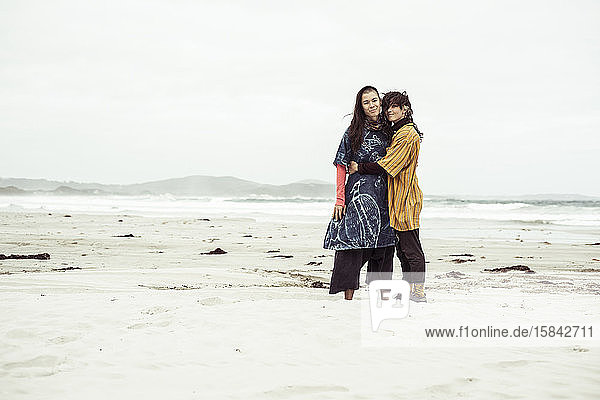 Gleichgeschlechtliches lesbisches Paar umarmt sich bei wildem Strandabenteuer im Wind