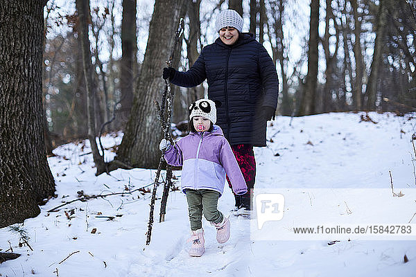 Mutter und Kind wandern auf einem verschneiten Waldweg.