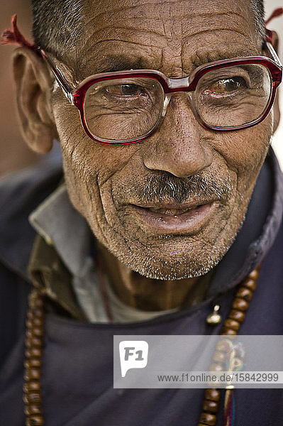 Alter buddhistischer Mann mit typischem Gewand und Brille