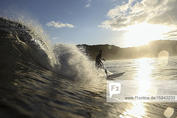 Surfer auf einer Welle zur Zeit des Sonnenuntergangs