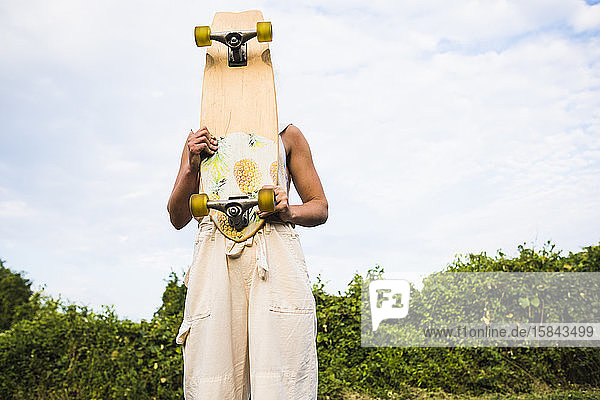 Junge Frau mit Skateboard im Sommer