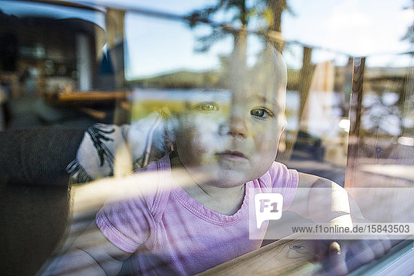 Junges Kleinkind schaut neugierig erwartungsvoll aus dem Fenster.