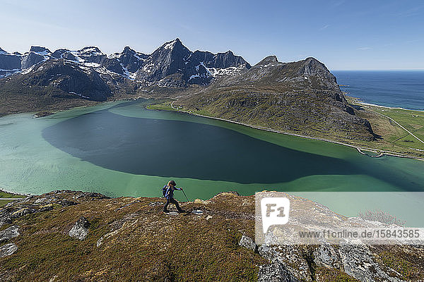 Wanderin beim Wandern über das farbenprächtige Wasser des Flakstadpollen  FlakstadÃ¸y  Lofoten-Inseln  Norwegen