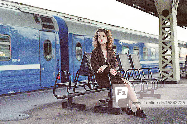 Eine Frau  die auf einem Bahnhof in der Nähe eines Zuges sitzt