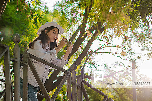 Junge Frau macht mit ihrem Smartphone ein Foto in einem Park. Freizeit  Lebensstil  Technologie