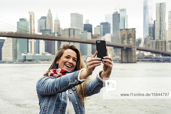 attraktive Frau  die ihr Smartphone benutzt  mit der Skyline von New York im Hintergrund