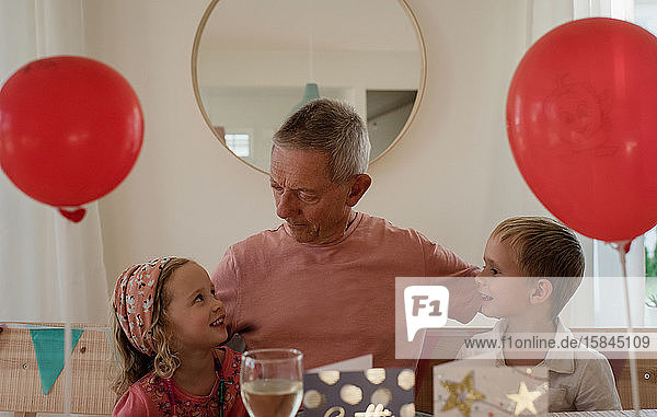 Großvater feiert seinen Geburtstag mit seinen Enkelkindern zu Hause