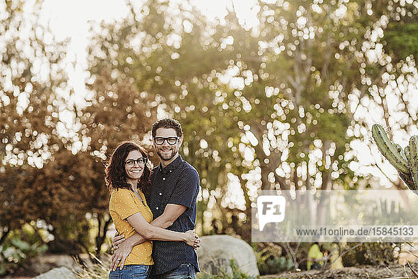 Portrait of husband and wife smiling at camera in sunny cactus garden