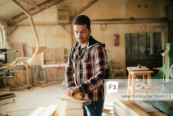 Young handsome carpenter flattening wood