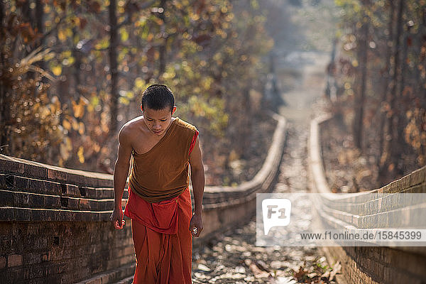 A young Buddhist monk climbing the stairway leading to Wat Phra Non temple in Mae Hong Son  Thailand.