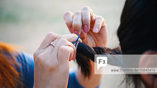 Close-up view hands of mother styling her daughter's hair