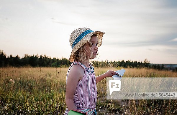 portrait of a young girl playing with paper planes in a meadow