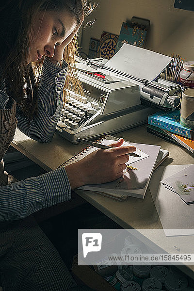 Junge Frau schreibt im Büro in der Nähe einer Schreibmaschine