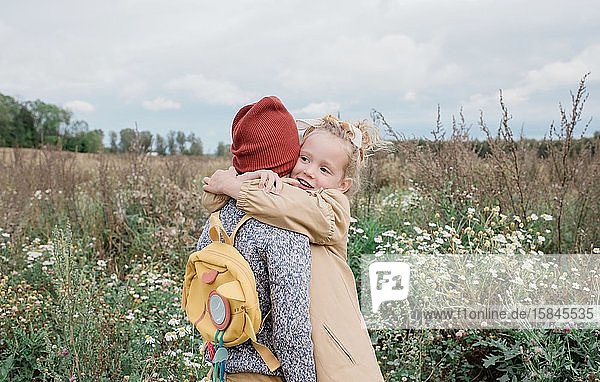 Eine Schwester  die ihren Bruder umarmte  stand im Herbst auf einem Feld mit Wildblumen