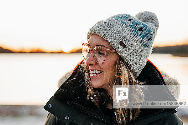 Porträt einer Frau  die bei Sonnenuntergang mit Schnee im Haar lächelt