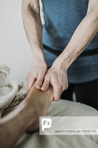Therapeutin benutzt Hände  um den Fuß des Klienten zu massieren
