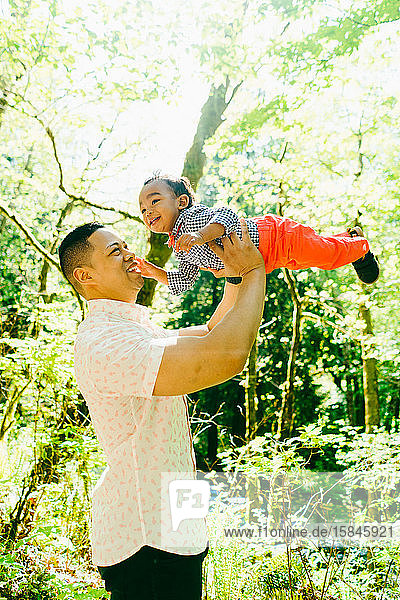 A father and baby son play together outside on a summer day