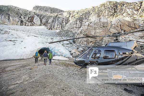 Ein Bergführer nähert sich mit Tourenkunden einer Gletschereishöhle.